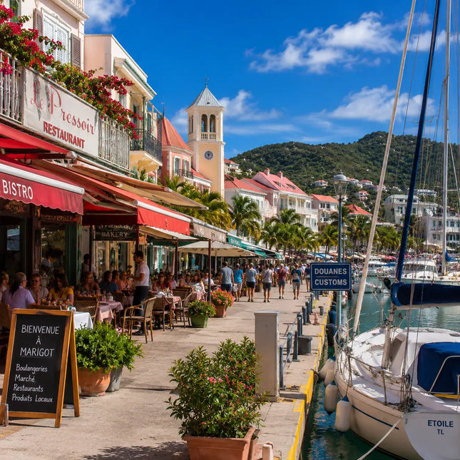 Waterfront promenade in Marigot Harbor featuring French cafés, restaurants, customs facilities, marina docks, and the vibrant cruising culture of Saint Martin's French side.