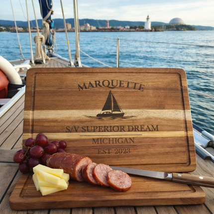 Marquette Michigan sailboat cutting board displayed on boat with Lake Superior lifestyle setting