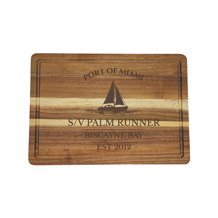 Wooden cutting board with engraved text and sailboat illustration on a white background