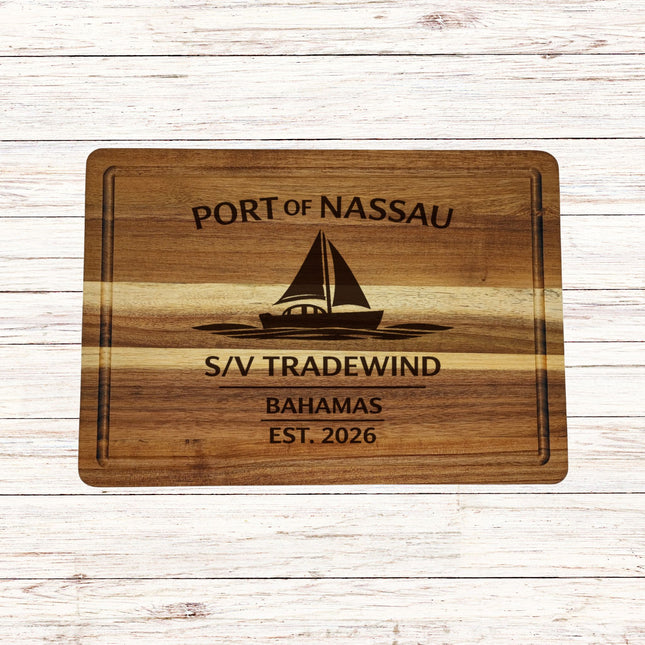 Wooden cutting board with engraved text and sailboat illustration on a wooden surface