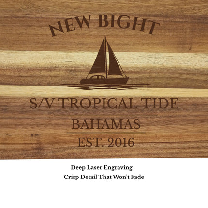 Close up of New Bight Bahamas sailboat cutting board engraving showing detailed sailboat design and acacia wood grain