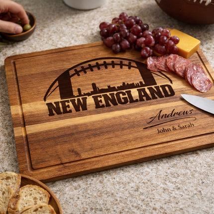 Personalized New England football cutting board in use on a kitchen counter with food, showing authentic laser engraving on acacia wood
