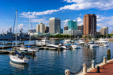 Norfolk Harbor marina with sailboats, yachts, naval ships, and downtown waterfront skyline along the Intracoastal Waterway on a sunny day.