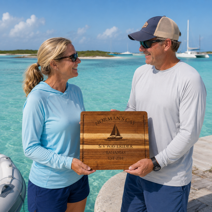 Norman’s Cay Bahamas personalized cutting board being exchanged as a gift near shallow turquoise anchorage water in the remote Exumas