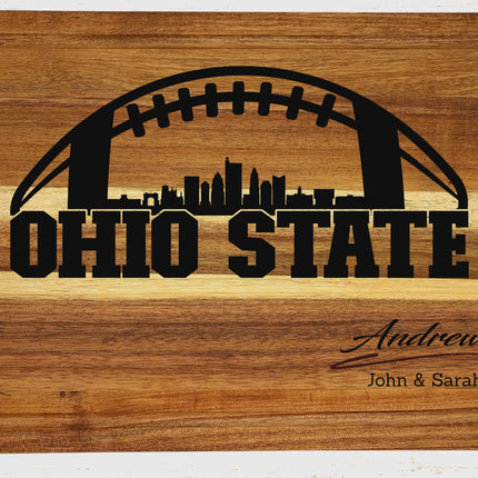 Close-up of dark brown laser engraved Ohio State football design showing skyline detail and personalized family name carved into solid acacia wood cutting board

