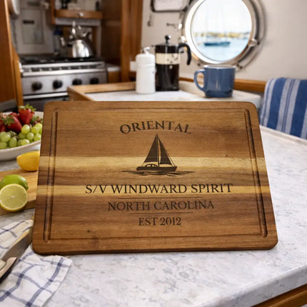 Oriental personalized sailboat cutting board displayed inside a sailboat galley with ocean view through porthole and nautical setting