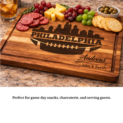 Personalized Philadelphia football cutting board used as a charcuterie serving board with meats cheese grapes and crackers on a kitchen countertop