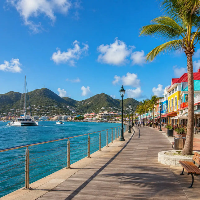 Colorful waterfront boardwalk in Philipsburg Sint Maarten featuring harbor views, sailboats, palm trees, waterfront shops, and Caribbean island culture