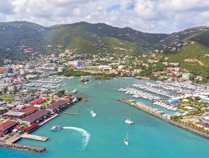 Aerial view of Road Harbour and Road Town, Tortola, British Virgin Islands, featuring marinas, charter yachts, turquoise water, and the surrounding green hills.