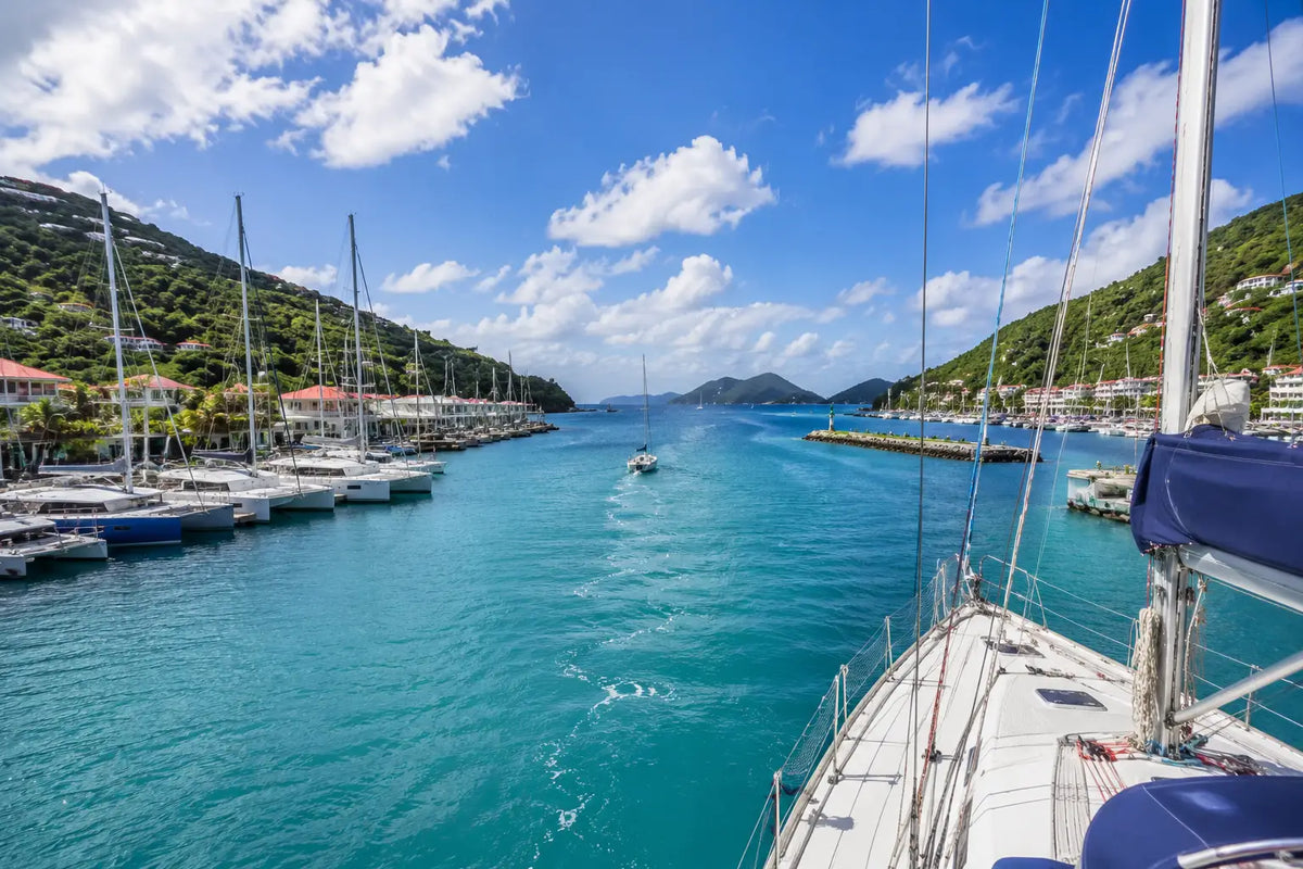 Sailboat departing Road Harbour toward Sir Francis Drake Channel, showcasing the crystal-clear waters and island scenery that make the British Virgin Islands a world-class cruising destination.