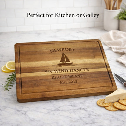 Personalized sailboat cutting board displayed in coastal kitchen setting with food preparation and nautical decor