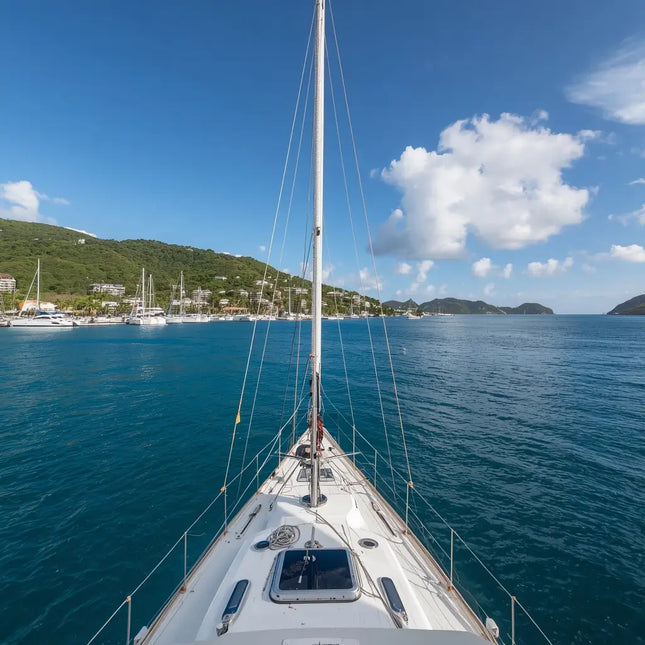 View from the deck of a sailboat approaching Charlotte Amalie Harbor in St. Thomas, U.S. Virgin Islands, with the waterfront and tropical hills ahead.