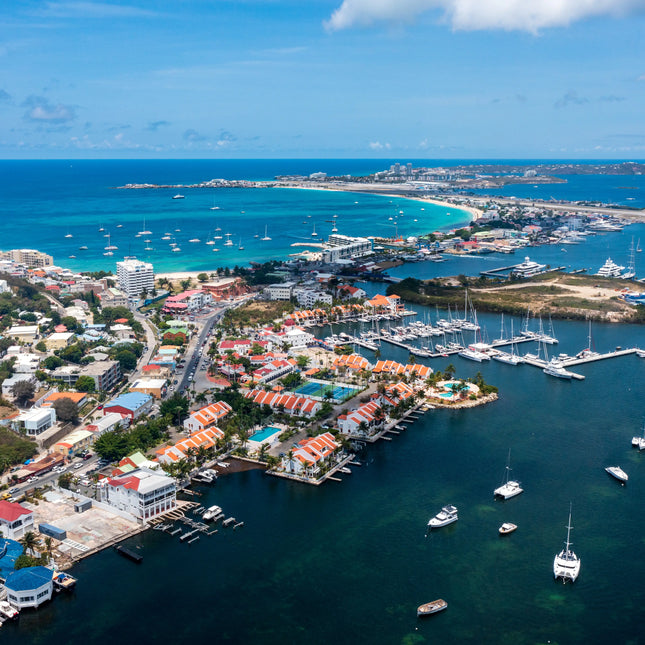 Aerial view of Simpson Bay Lagoon in Saint Martin showing sailboats, marinas, turquoise Caribbean waters, and the lagoon entrance.