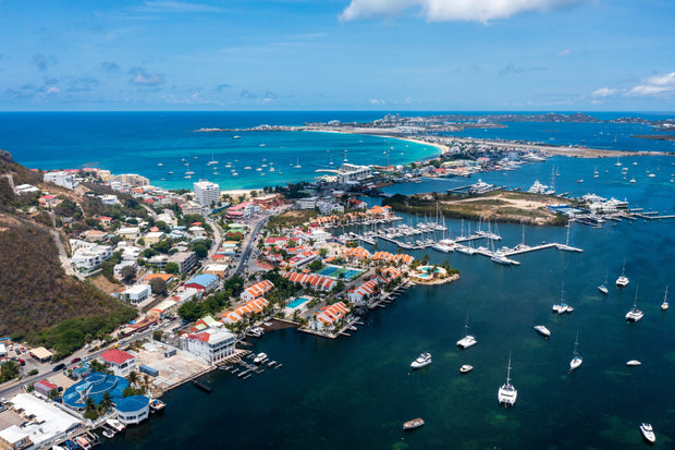 Aerial view of Simpson Bay Lagoon in Saint Martin showing sailboats, marinas, turquoise Caribbean waters, and the lagoon entrance.
