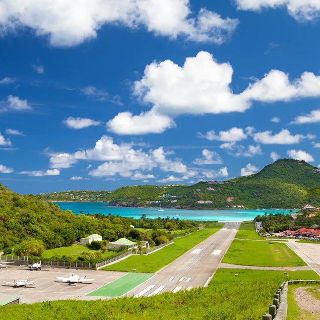 View of Gustaf III Airport overlooking St. Jean Bay in St. Barths, featuring the famous runway approach above the beach and turquoise Caribbean waters.