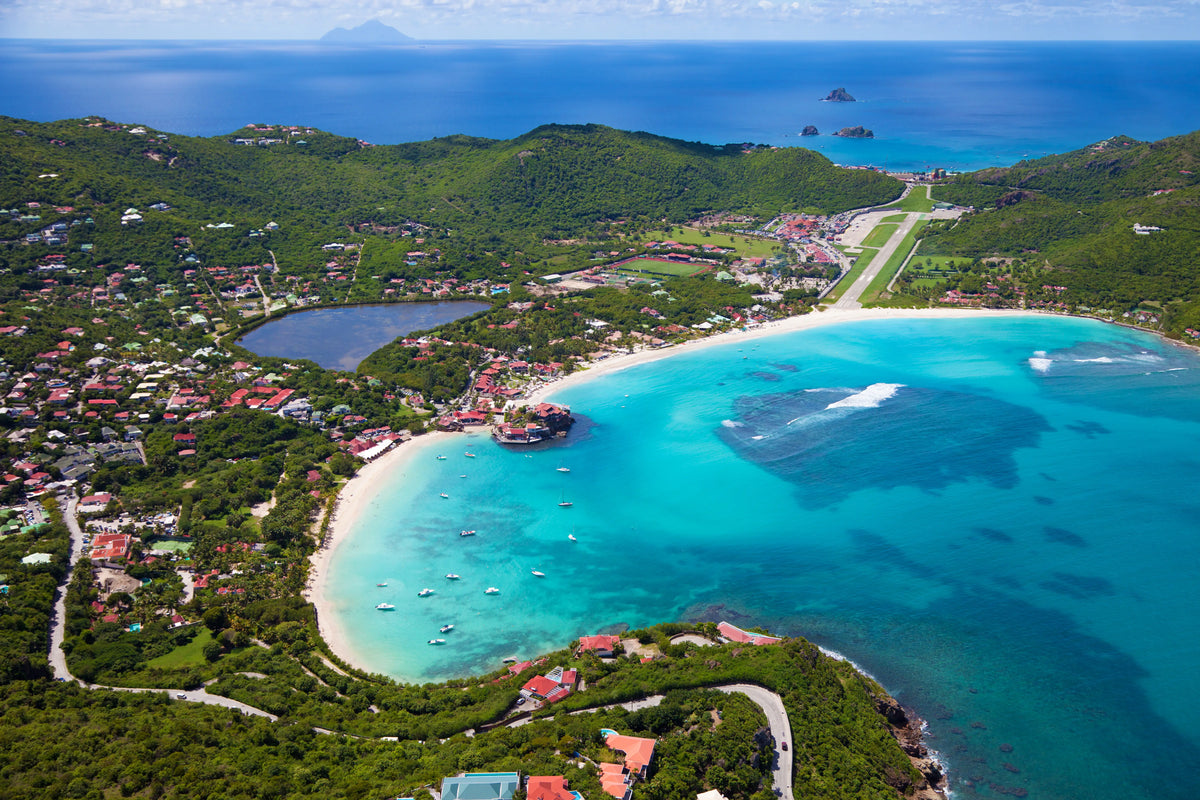 Aerial view of St. Jean Bay in St. Barths featuring turquoise waters, white sand beaches, anchored sailboats, Eden Rock, and the famous Gustaf III Airport runway.