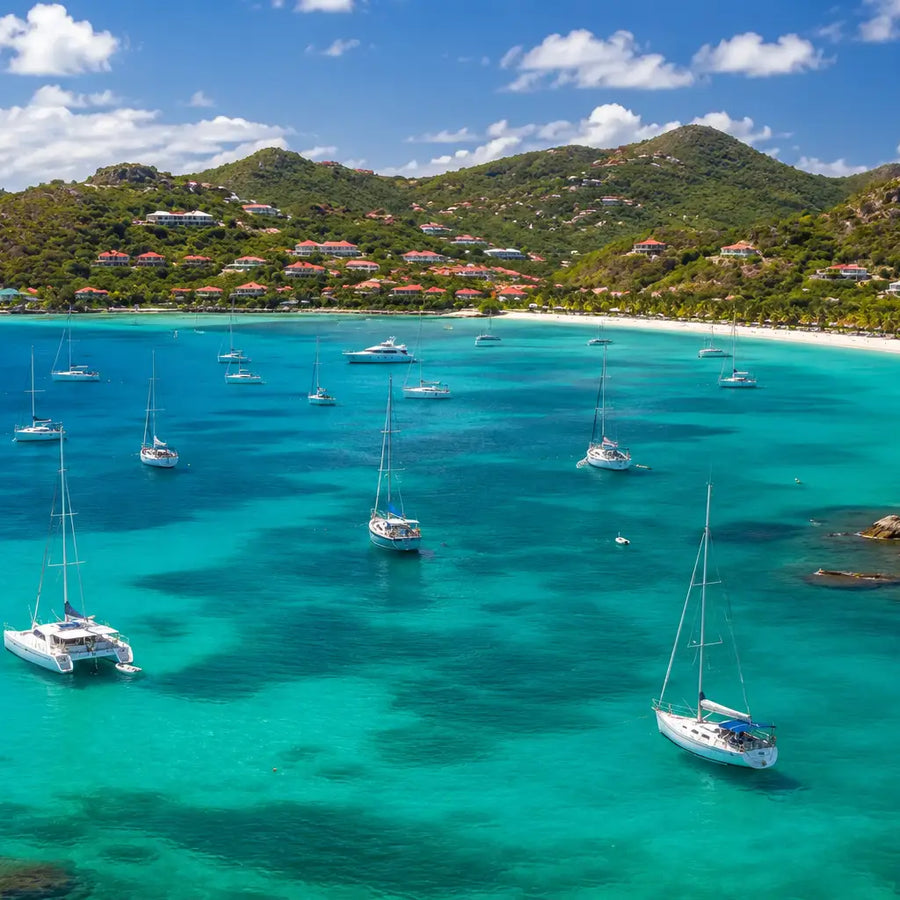 Sailboats and catamarans anchored in the turquoise waters of St. Jean Bay, one of St. Barths' most popular cruising destinations.