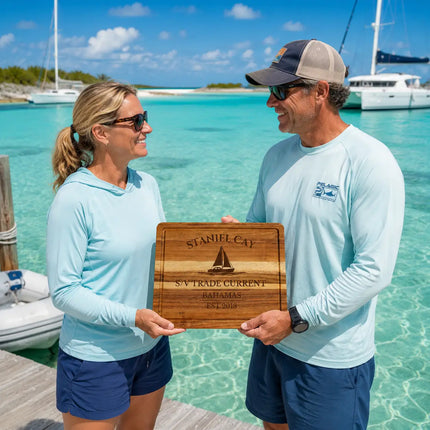 Staniel Cay Bahamas personalized cutting board being exchanged as a gift near shallow turquoise water and anchored sailboats in the Exumas