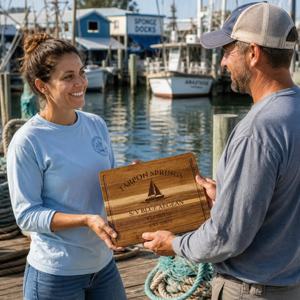 Tarpon Springs Florida personalized cutting board being given as a gift on a working dock with fishing boats ropes and waterfront activity